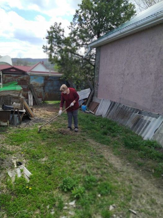 Сестра хозяйка Бедрина Л.И.  помогает пенсионеру Бондареву Н.В. убирать двор.